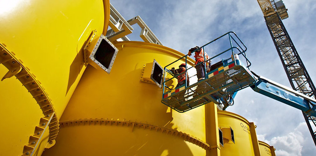 Employees working outside of large yellow drums